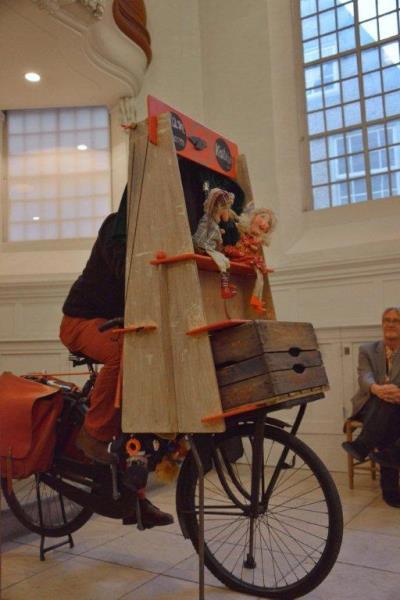 De poppenspeler op de fiets in actie